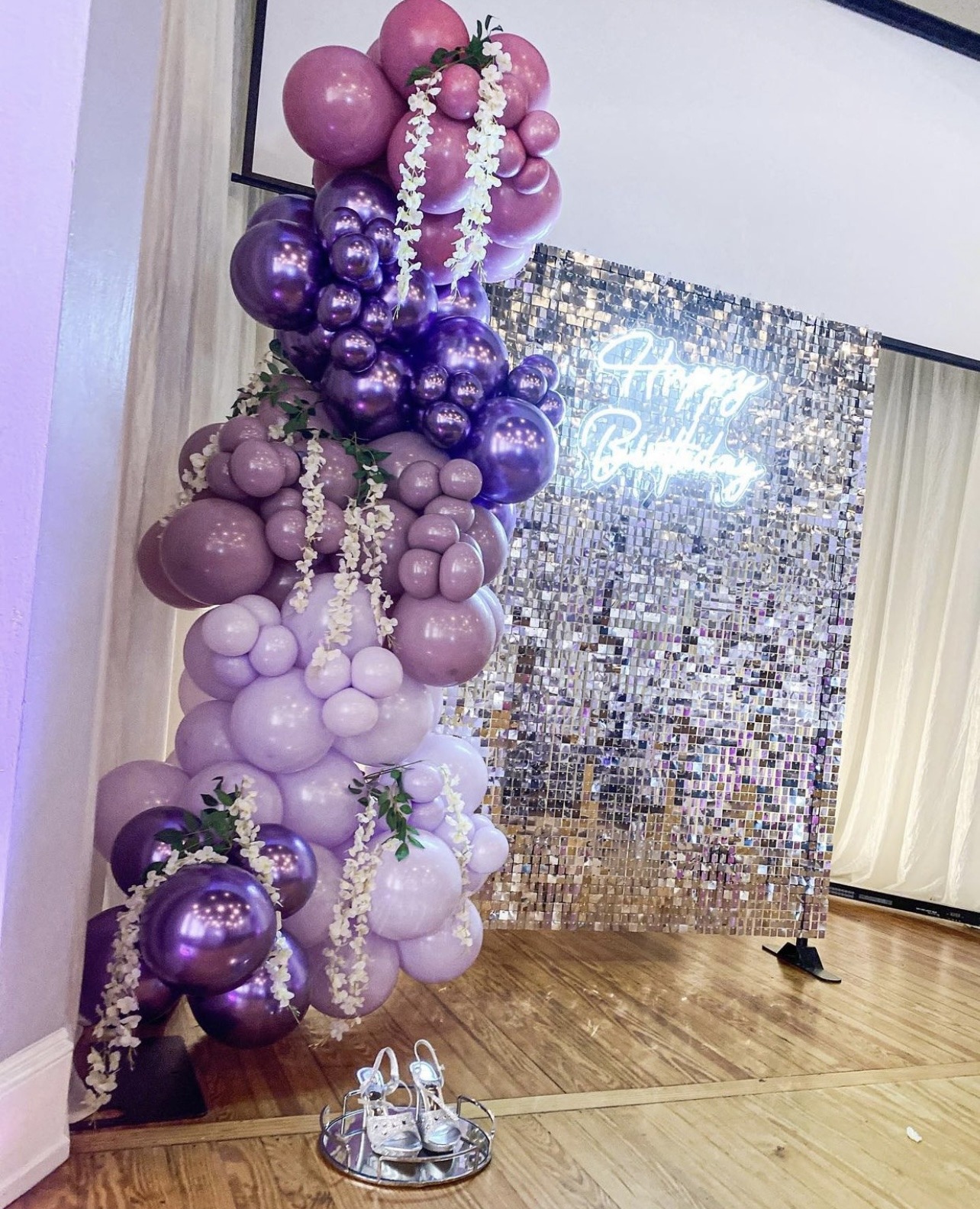 Celebration Balloon Arch and Sequin Backdrop - The Main Event Company Purple and pink balloon decor beside a shimmering party photo backdrop