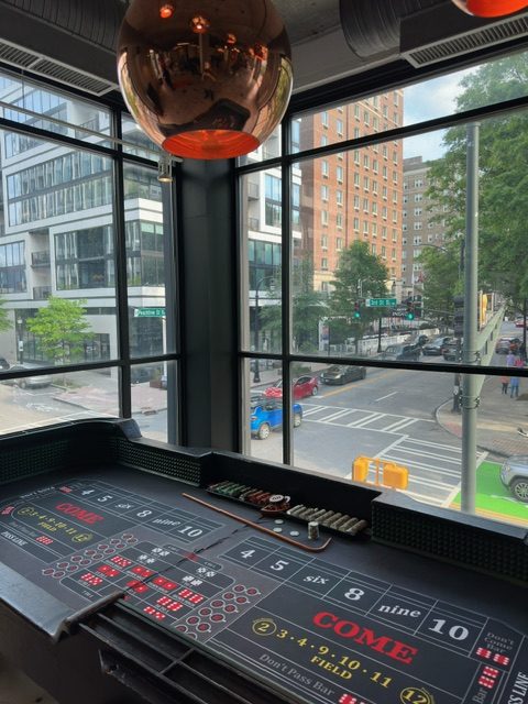 ballys - The Main Event Company Craps table beside floor-to-ceiling windows overlooking the city