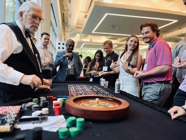 caesars - The Main Event Company A roulette dealer and guests gathered around a casino table