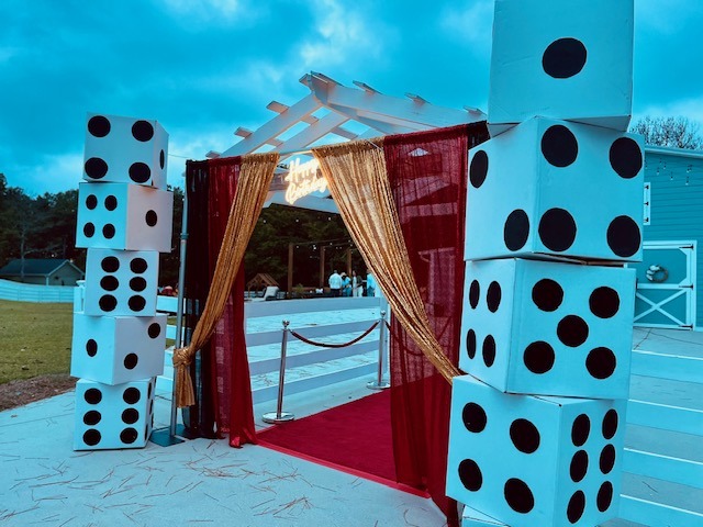 casino-entrance-oversized-dice-red-carpet-gold-drapes - The Main Event Company Casino-themed entrance with oversized dice, a red carpet, and gold drapes