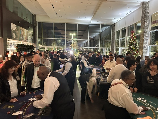 casino-night-guests-professional-dealers-windowed-venue - The Main Event Company Guests playing casino games with professional dealers in a window-lined venue