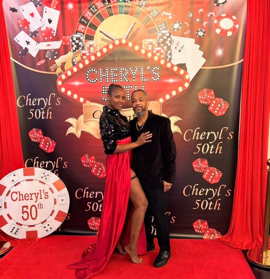 cheryls-50th-birthday-casino-backdrop-couple - The Main Event Company Two guests posing at a casino-themed 50th birthday backdrop