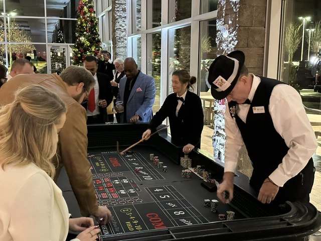 craps-dealer-guests-busy-casino-night - The Main Event Company A professional dealer hosting guests at a craps table during a casino night
