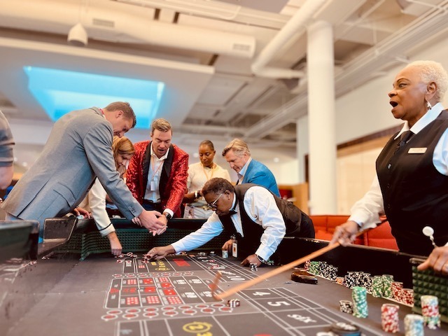 craps-table-dealer-guests-ballroom-casino-party - The Main Event Company A dealer and guests gathered around a craps table in a ballroom