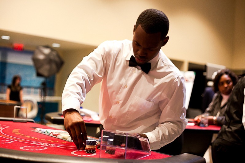 LeahAndMark.com - The Main Event Company Professional roulette dealer hosting guests at a red casino table