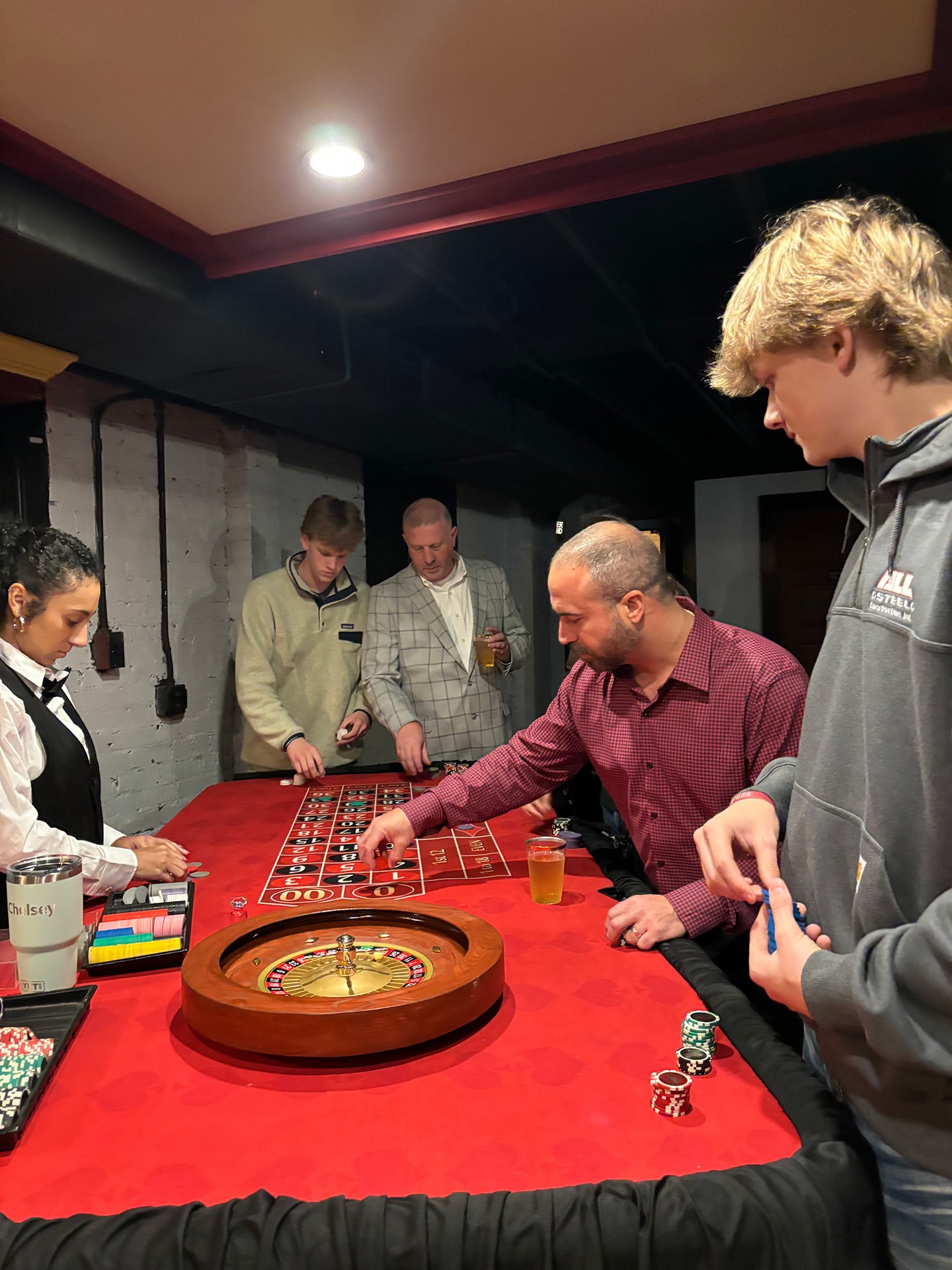 roulette-guests-red-table - The Main Event Company Guests gathered around a red roulette table