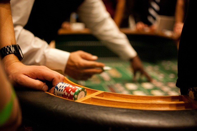 tropicana - The Main Event Company Roulette wheel and chips with guests playing at a casino table